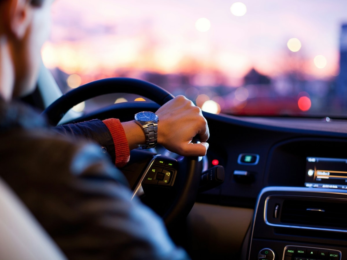 A driver's hands on the wheel on an open road
