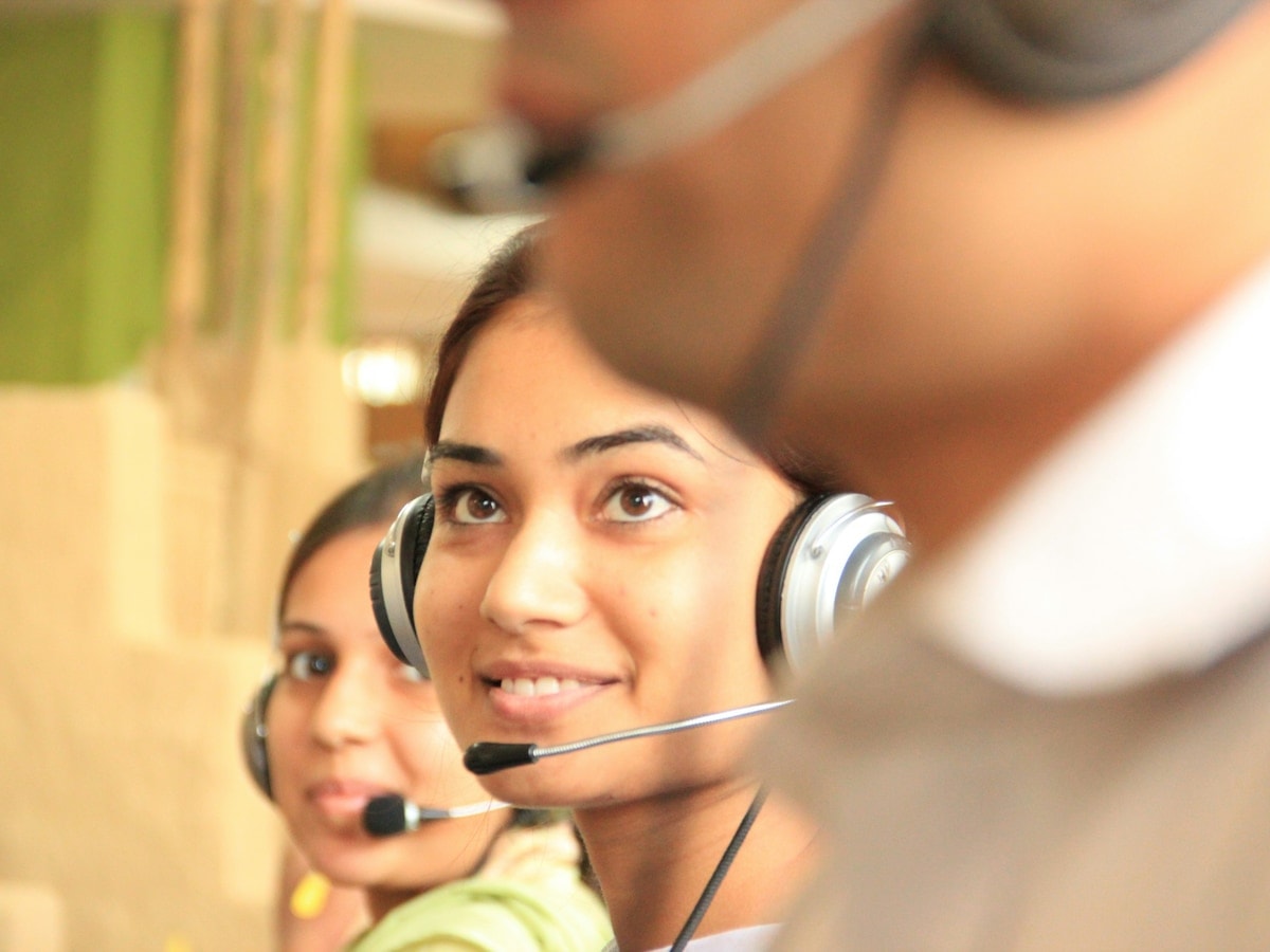 Two support agents wearing headsets at their desks