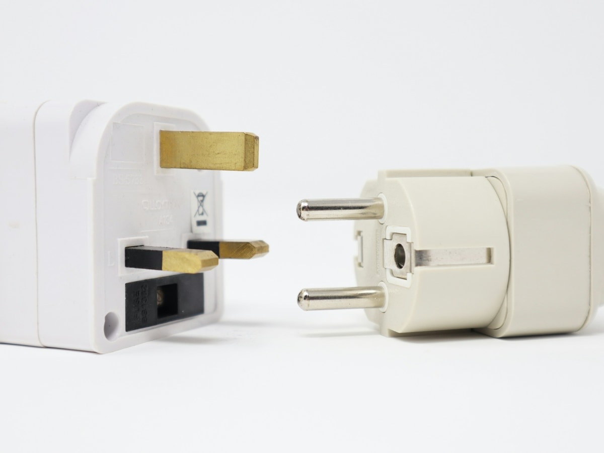 Two mains plug adapters on a plain background